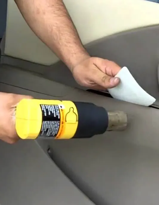 Technician working on a car door panel with a heat gun