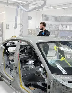 Technicians repairing a vehicle body shell on a frame bench
