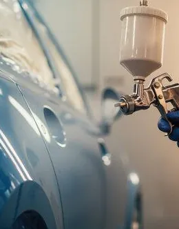 Painter spraying a dark blue car with a paint gun