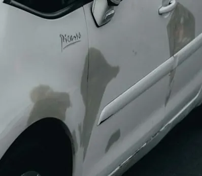 Peeling paint on a white car panel