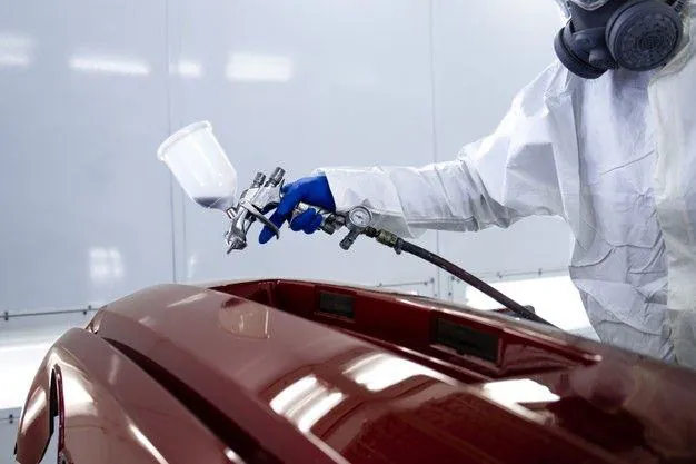 Painter spraying a red car bonnet